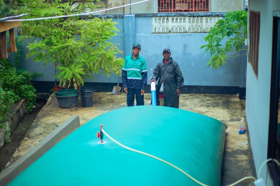 Tanzania Kwanza staff beside a live biodigester plant